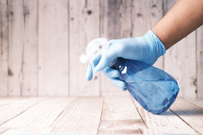Gloved hand cleaning a surface with a spray bottle